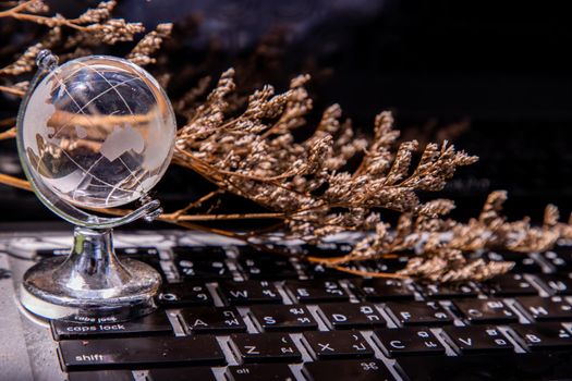 Glass crystal globe on Laptop keyboard. Concept for global communication and business. Selective focus.