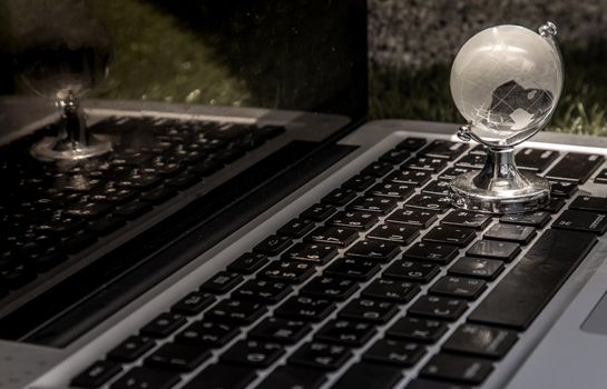Glass crystal globe on Laptop keyboard. Concept for global communication and business. Selective focus.
