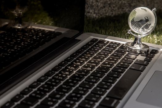 Glass crystal globe on Laptop keyboard. Concept for global communication and business. Selective focus.