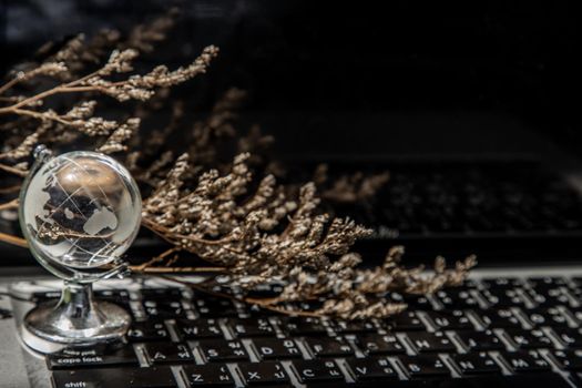 Glass crystal globe on Laptop keyboard. Concept for global communication and business. Selective focus.