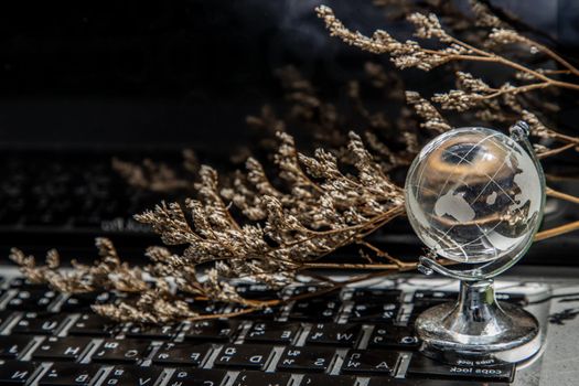 Glass crystal globe on Laptop keyboard. Concept for global communication and business. Selective focus.