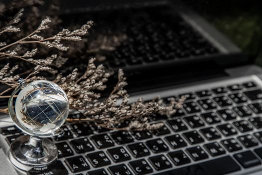Glass crystal globe on Laptop keyboard. Concept for global communication and business. Selective focus.