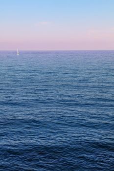 Tranquil sunset seascape scene with pastel pink sky and calm sea, high angle view
