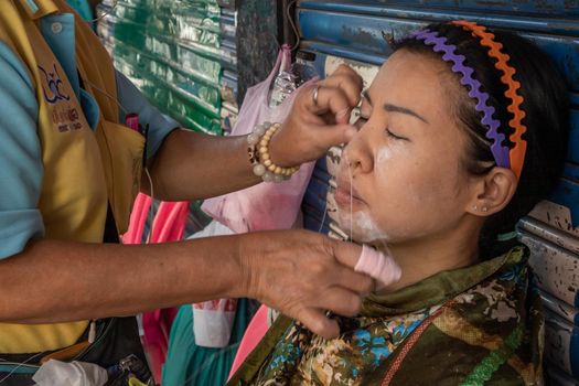 Bangkok, thailand - Feb 16, 2020 : Yaowarat street merchant service customer face hair removal beauty by yarn. Ancient chinese - style hair removal, Chinese traditional “ Mang Ming “ style.