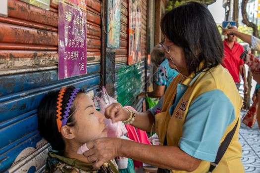 Bangkok, thailand - Feb 16, 2020 : Yaowarat street merchant service customer face hair removal beauty by yarn. Ancient chinese - style hair removal, Chinese traditional “ Mang Ming “ style.