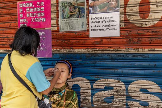 Bangkok, thailand - Feb 16, 2020 : Yaowarat street merchant service customer face hair removal beauty by yarn. Ancient chinese - style hair removal, Chinese traditional “ Mang Ming “ style.