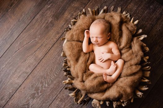 Newborn sleeping on his back in a brown basket at a newborn photoshoot. High quality photo