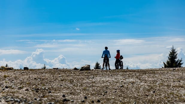 Two people standing with bicycles on the edge of quartz mine at sunny day