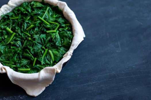 raw spinach pie preparation Standing wooden table background Copy space for text