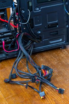 bunch of computer power supply wires sticking out from opened black pc case - close-up with selective focus.