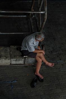 Bangkok, Thailand - July 10, 2019 : Senior man Sit and relax under basketball backboard at community stadium. No focus, specifically.