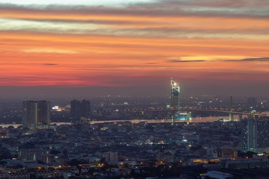 Bangkok, thailand - Dec 23, 2020 : Aerial view of Bangkok city Overlooking Skyscrapers and the Bridge crosses the Chao Phraya river with bright glowing lights at dusk. No focus, specifically.