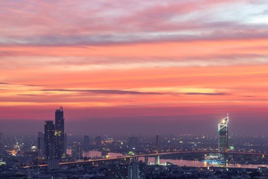 Bangkok, thailand - Dec 23, 2020 : Aerial view of Bangkok city Overlooking Skyscrapers and the Bridge crosses the Chao Phraya river with bright glowing lights at dusk. No focus, specifically.