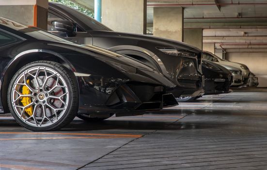 Bangkok, Thailand - 06 Jan 2021 : The side of Wheel of Black Lamborghini Sports Car parked in the parking lot. Selective focus.