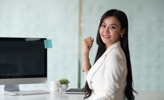 Portrait of excited business woman smiling and raised hands up celebrate , successful winner businesswoman look at camera.