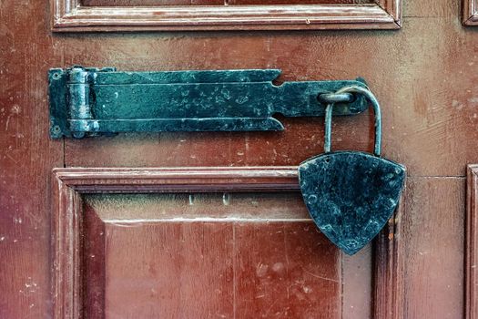 Black padlock closure on a mahogany wood door