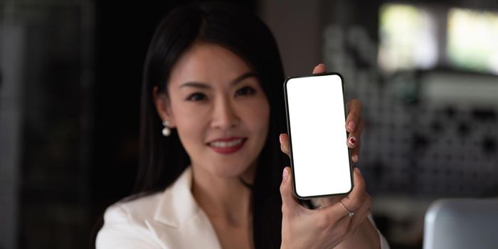 Asian businesswoman showing a blank smartphone screen. Focus on smartphone