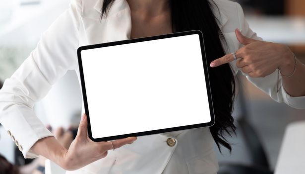 Businesswoman shows the digital tablet with blank screen in a front view shot
