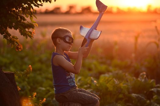 A boy plays with a plane at sunset. Little pilot aviator.