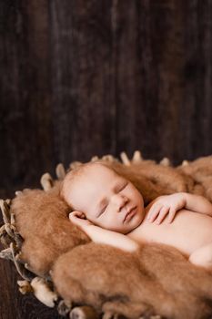 Newborn baby girl sleeping on a wool blanket in a wooden basket. High quality photo