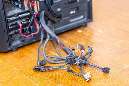 bunch of computer power supply wires sticking out from opened black pc case - close-up with selective focus.