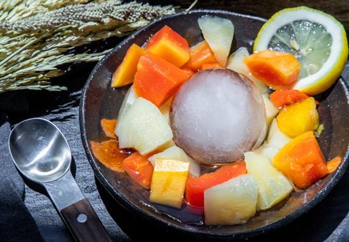 Tropical fresh fruit salad served with corn on black ceramic bowl in dark background.  Selective focus.