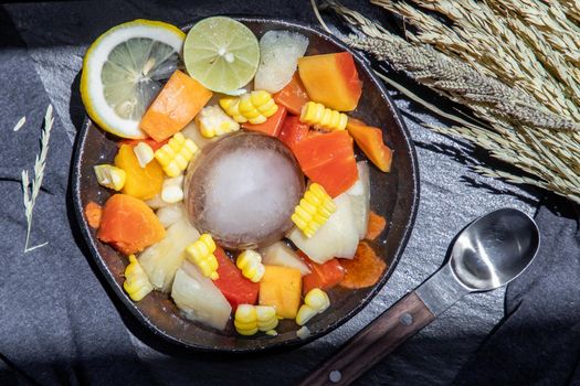 Tropical fresh fruit salad served with corn on black ceramic bowl in dark background.  Selective focus.