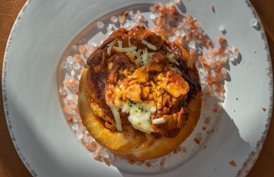Homemade pizza buns topped with tomato sauce, ham, sausage, green onion and mozzarella cheese with himalayan pink salt on classic white plate.