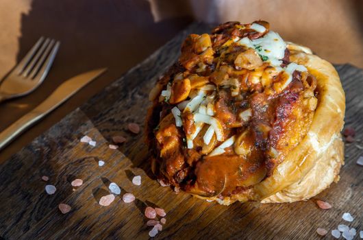 Homemade pizza buns topped with tomato sauce, ham, sausage, green onion and mozzarella cheese with himalayan pink salt on rustic wooden board.