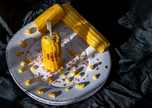 Grilled corn on the cob  on classic white plate over dark background. Ideas for barbecue and grill parties, Barbecue concept.