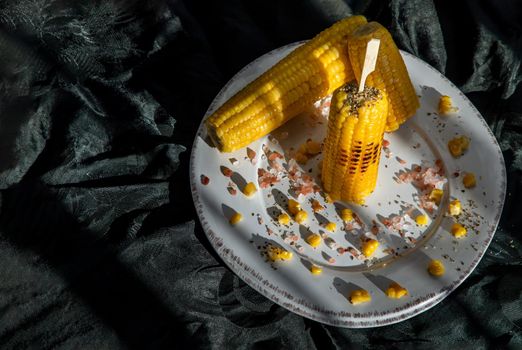 Grilled corn on the cob  on classic white plate over dark background. Ideas for barbecue and grill parties, Barbecue concept.