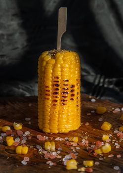 Grilled corn on the cob  on rustic wooden board   over dark background. Ideas for barbecue and grill parties, Barbecue concept.