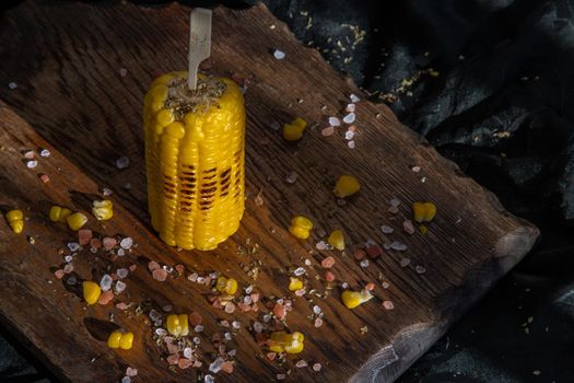 Grilled corn on the cob  on rustic wooden board   over dark background. Ideas for barbecue and grill parties, Barbecue concept.