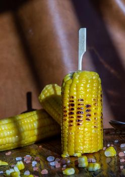 Grilled corn on the cob  on rustic wooden board over brown leather background.  Ideas for barbecue and grill parties, Barbecue concept.