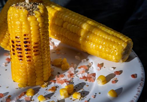 Grilled corn on the cob  on classic white plate over dark background. Ideas for barbecue and grill parties, Barbecue concept.