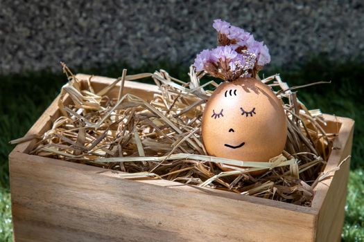The happy egg is lying on dry straw.  Happy and relaxing concept.