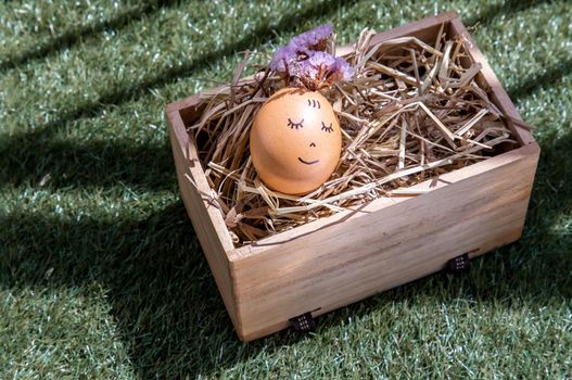 The happy egg is lying on dry straw.  Happy and relaxing concept.
