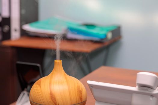 Using an electric humidifier on the desk in the office. Steam flows upwards