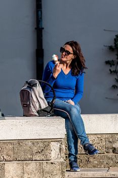 terni,italy march 25 2021:sitting girl eats ice cream with sunglasses