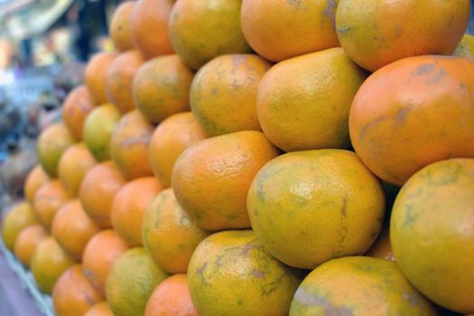 A closeup shot of a pile of fresh oranges in a market place