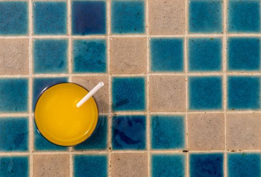 A glass of fresh orange juice for a refreshment on swiwming pool. Outdoor swimming pool background.
