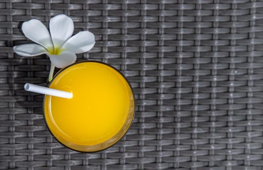 A glass of fresh orange juice with flower for a refreshment on balck background. leisure activity.