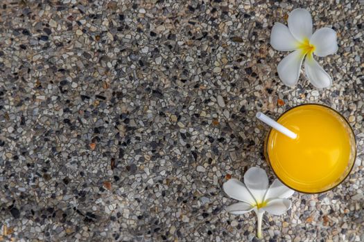 A glass of fresh orange juice with flower for a refreshment on stone background. leisure activity.