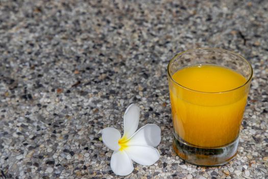 A glass of fresh orange juice with flower for a refreshment on stone background. leisure activity.