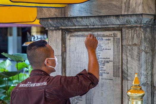 Bangkok, Thailand - Jun 19, 2020 : Temple staff is writing the donator name on the wall.
