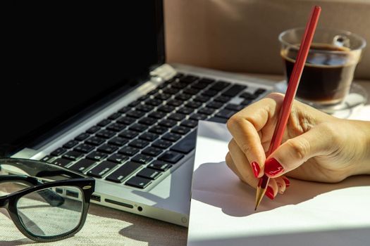 Hand of business woman writing on paper at her workstation. business concept.