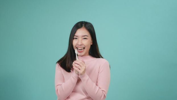 Asian young beautiful woman smile brushing teeth dancing enjoying music,  Female brush teeth singing song, dance and have fun isolated on blue background, lifestyle dental hygiene and health concept