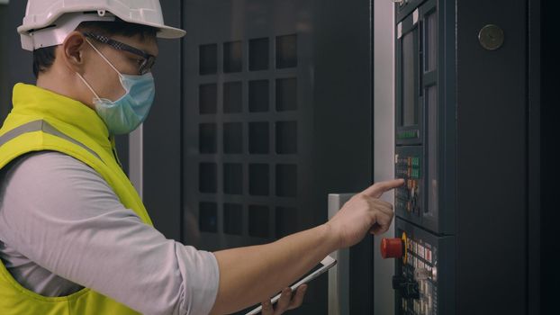 Asian factory worker man operating automated programming CNC milling control machine industry center at tool workshop manufacturing