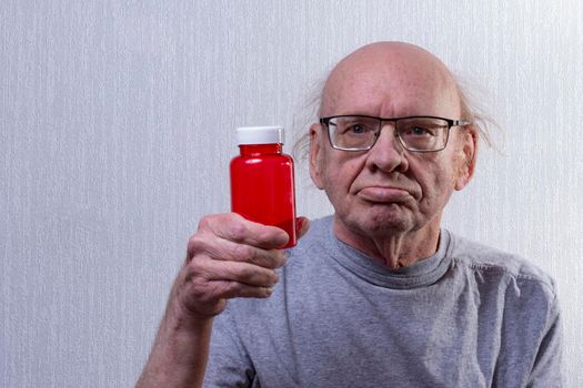 He's holding an empty pill jar in his hand. Portrait.