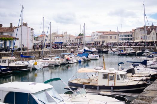 View on the harbor of Saint-Martin-de-Ré with boats and people walking on a sunny summerday